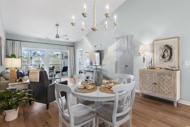 dining area with hardwood / wood-style floors and ceiling fan with notable chandelier