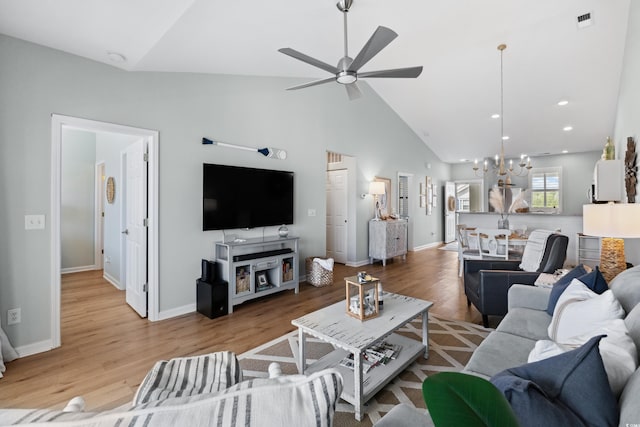 living room with light hardwood / wood-style flooring, high vaulted ceiling, and ceiling fan with notable chandelier