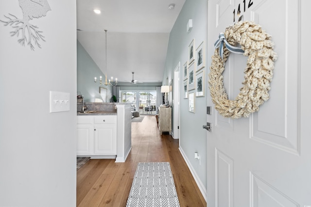 hallway featuring light hardwood / wood-style flooring, lofted ceiling, and sink