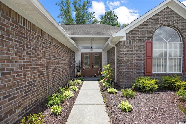 view of exterior entry featuring french doors and brick siding