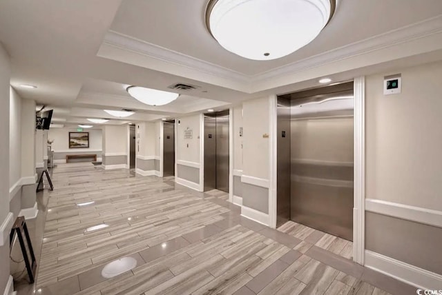 hall with crown molding, elevator, and a tray ceiling