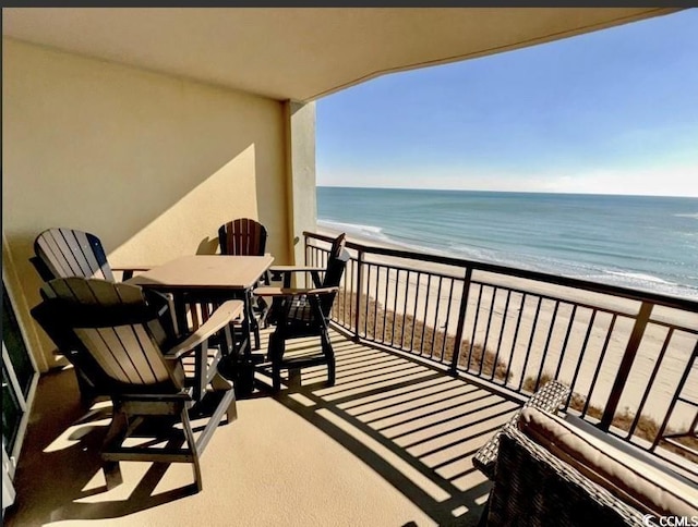 balcony with a water view and a view of the beach