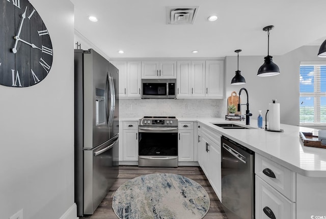 kitchen featuring backsplash, stainless steel appliances, sink, decorative light fixtures, and white cabinets