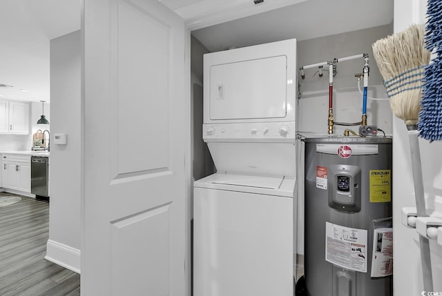 laundry area with hardwood / wood-style floors, sink, stacked washer and dryer, and water heater