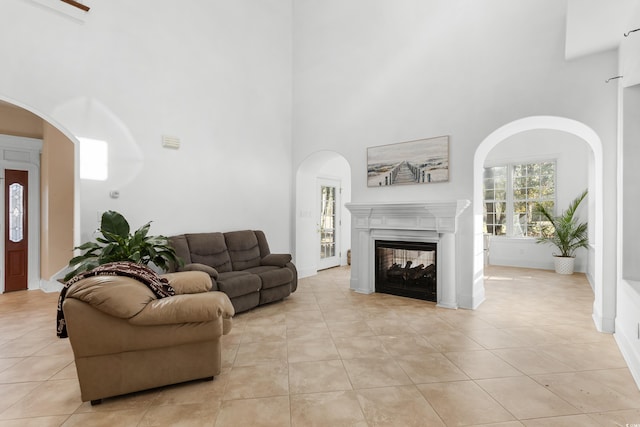 tiled living room with a multi sided fireplace and a high ceiling