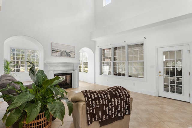 living room with a multi sided fireplace, a high ceiling, and light tile patterned flooring