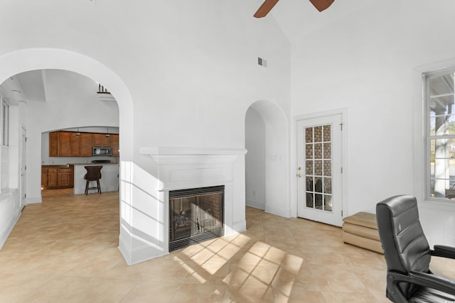 tiled living room with ceiling fan and high vaulted ceiling