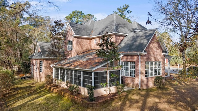 back of house featuring a lawn and a sunroom