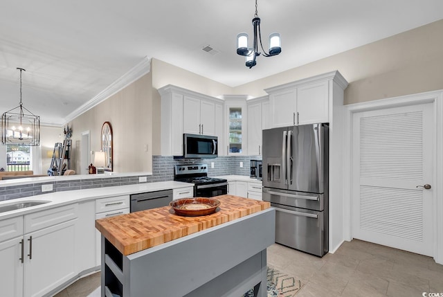 kitchen featuring white cabinetry, tasteful backsplash, a chandelier, a kitchen island, and appliances with stainless steel finishes