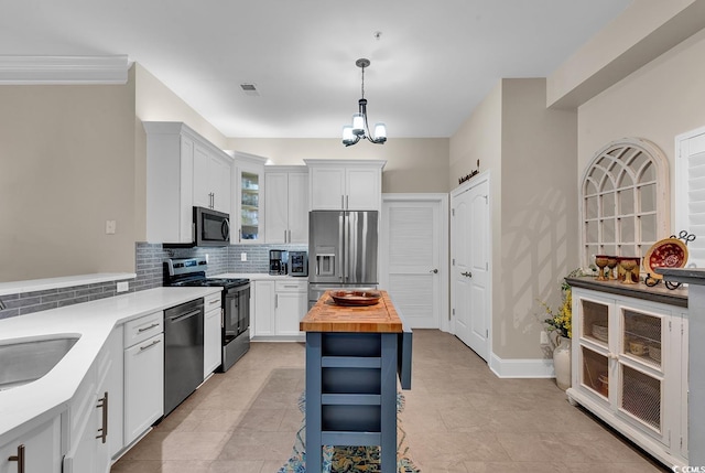 kitchen featuring white cabinetry, stainless steel appliances, wood counters, pendant lighting, and decorative backsplash