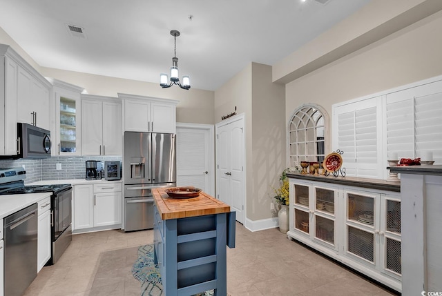 kitchen with stainless steel appliances, wood counters, pendant lighting, decorative backsplash, and white cabinets