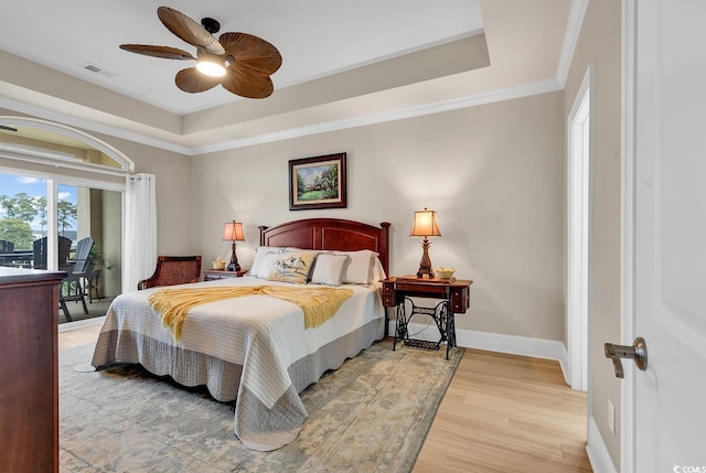 bedroom with hardwood / wood-style flooring, ceiling fan, a raised ceiling, and crown molding