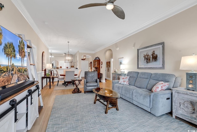 living room with light hardwood / wood-style floors, ceiling fan with notable chandelier, and ornamental molding