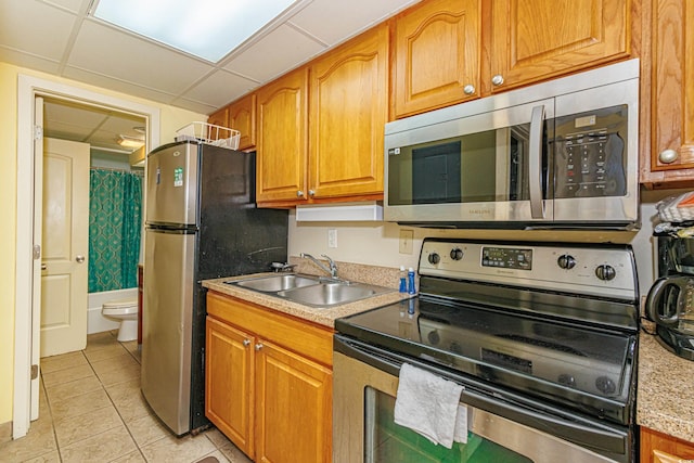 kitchen with sink, light tile patterned floors, a paneled ceiling, and appliances with stainless steel finishes