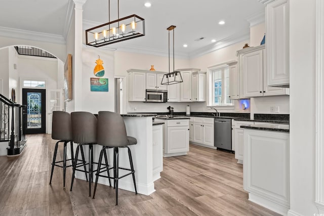 kitchen with pendant lighting, a kitchen breakfast bar, white cabinetry, and stainless steel appliances