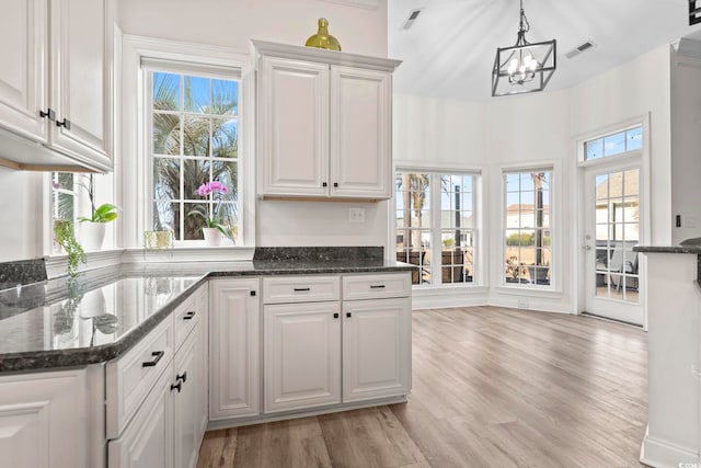 kitchen with white cabinets, light hardwood / wood-style floors, and decorative light fixtures