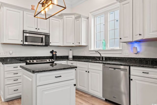 kitchen with white cabinetry, sink, dark stone countertops, appliances with stainless steel finishes, and ornamental molding