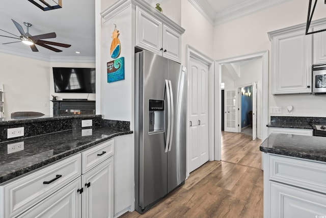 kitchen with wood-type flooring, stainless steel appliances, white cabinetry, and dark stone counters