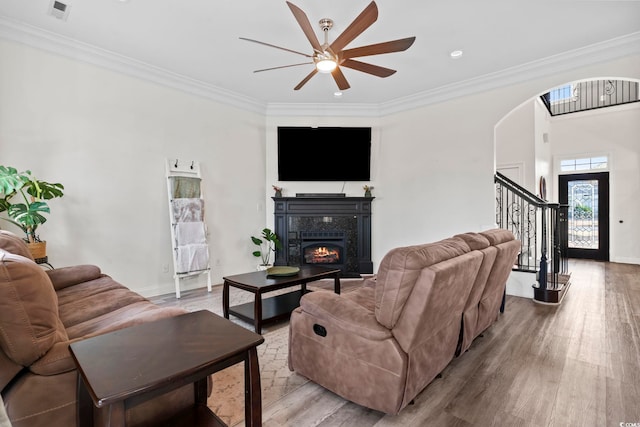 living room with ceiling fan, a fireplace, hardwood / wood-style floors, and ornamental molding