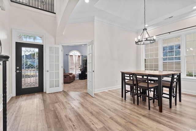 dining space featuring ornamental molding, french doors, a chandelier, and light hardwood / wood-style flooring