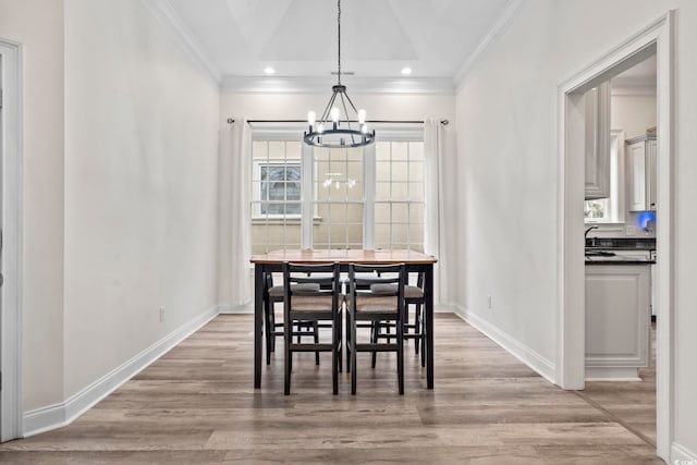 dining area featuring crown molding, sink, a chandelier, and light hardwood / wood-style flooring