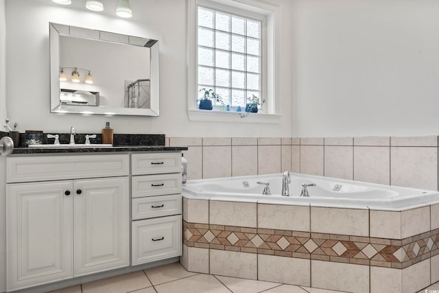 bathroom with tile patterned flooring, vanity, a healthy amount of sunlight, and tiled bath