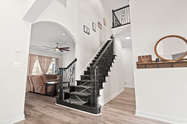 stairway with wood-type flooring, ceiling fan, and ornamental molding