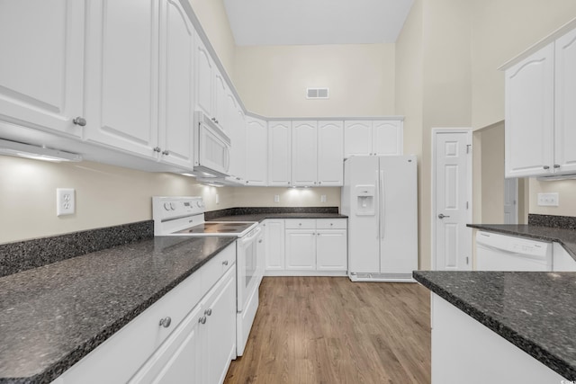 kitchen featuring white appliances, white cabinetry, and dark stone counters