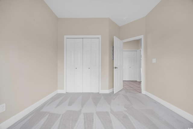 unfurnished bedroom with light carpet and a closet