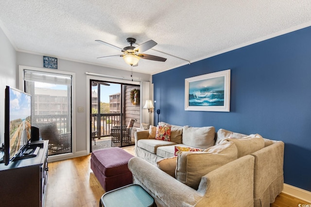 living room with a textured ceiling, a ceiling fan, baseboards, ornamental molding, and light wood-type flooring