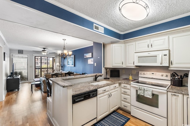 kitchen featuring white appliances, a sink, visible vents, ornamental molding, and light wood-type flooring