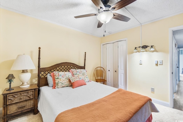 carpeted bedroom with ceiling fan, a textured ceiling, baseboards, and a closet