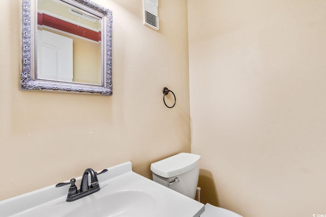 half bath featuring toilet, visible vents, and a sink