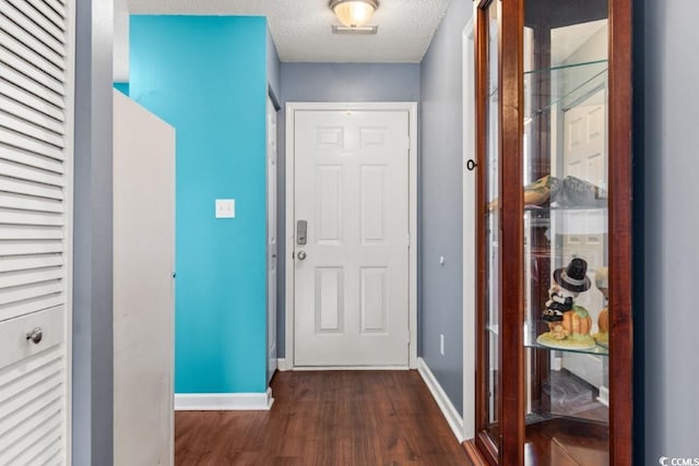 entryway with dark wood-style floors, a textured ceiling, and baseboards