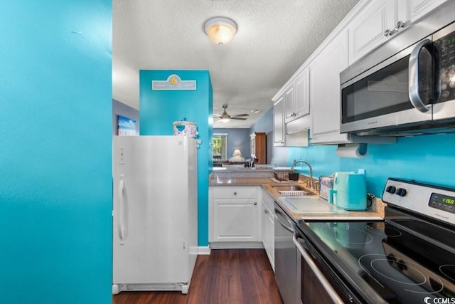 kitchen featuring dark wood-style flooring, a sink, white cabinetry, light countertops, and appliances with stainless steel finishes