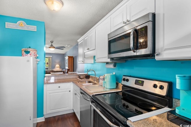 kitchen with a sink, stainless steel appliances, light countertops, and white cabinets