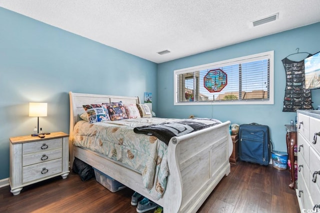 bedroom with visible vents, dark wood finished floors, and a textured ceiling