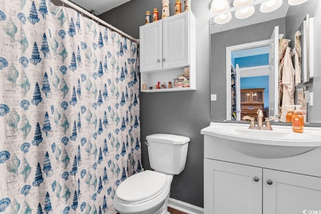 bathroom featuring baseboards, toilet, a shower with curtain, a textured ceiling, and vanity