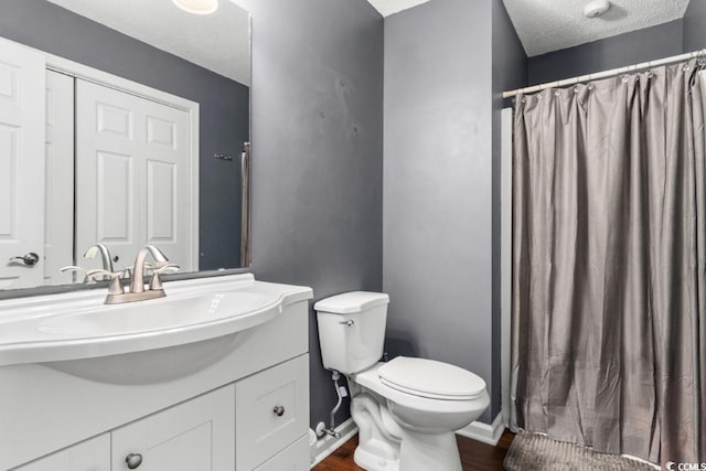 bathroom featuring baseboards, toilet, wood finished floors, a textured ceiling, and vanity