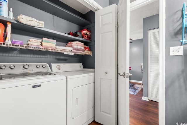 clothes washing area with baseboards, laundry area, dark wood finished floors, and washer and dryer