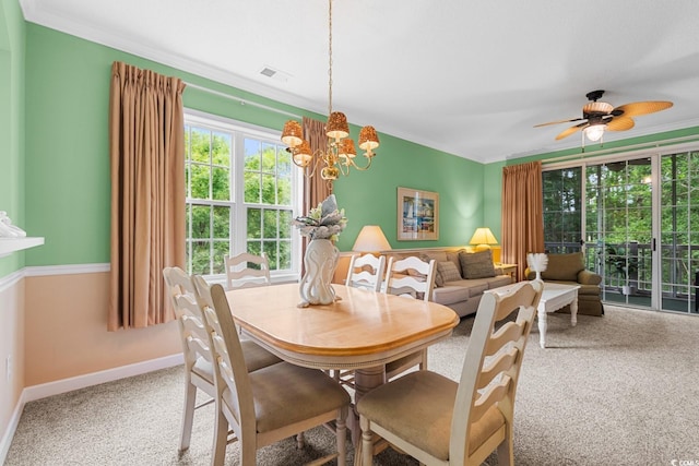 carpeted dining area featuring crown molding and ceiling fan with notable chandelier