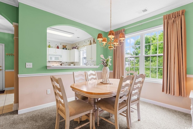 dining space featuring light carpet, crown molding, and a chandelier