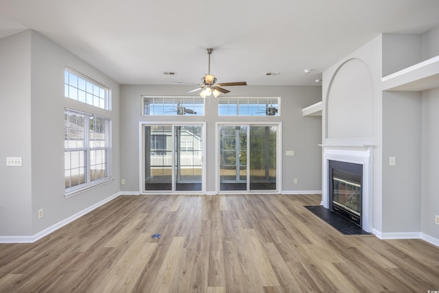 unfurnished living room featuring ceiling fan, light wood-type flooring, and a high ceiling