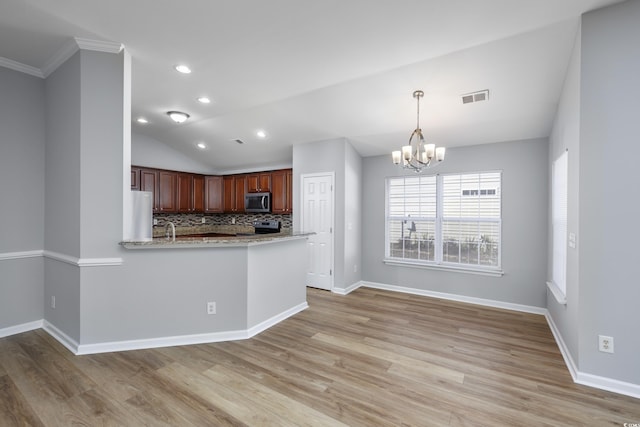 kitchen featuring lofted ceiling, an inviting chandelier, tasteful backsplash, kitchen peninsula, and stainless steel appliances