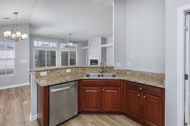 kitchen with kitchen peninsula, light stone countertops, stainless steel dishwasher, ceiling fan with notable chandelier, and sink