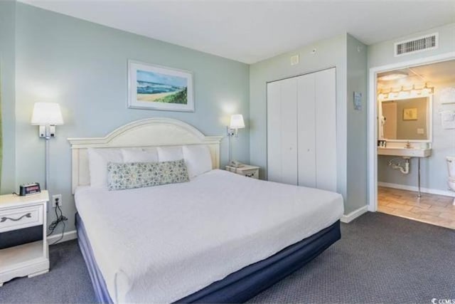 carpeted bedroom with ensuite bath and a closet