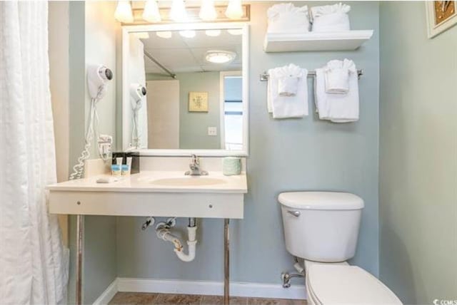 bathroom with a paneled ceiling, toilet, and sink