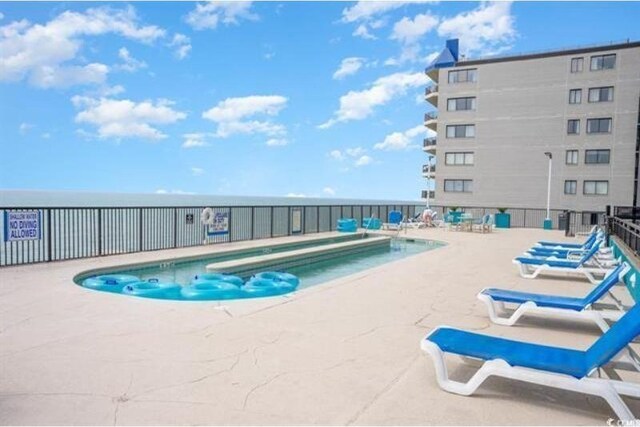 view of pool featuring a patio and a water view