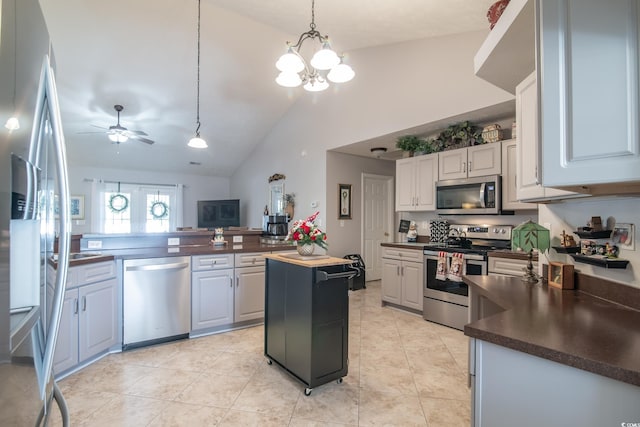 kitchen featuring butcher block countertops, white cabinetry, stainless steel appliances, and vaulted ceiling