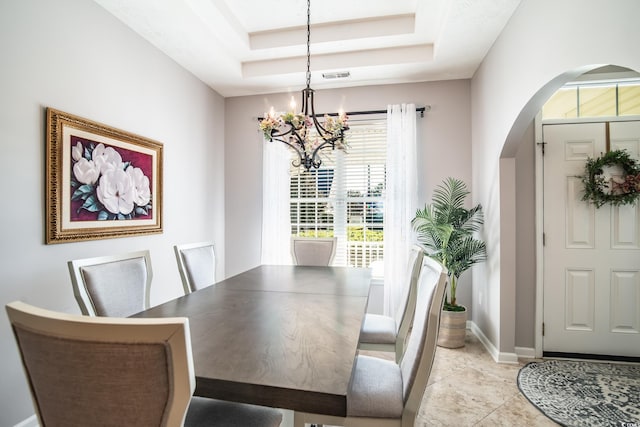 tiled dining space with a chandelier and a tray ceiling